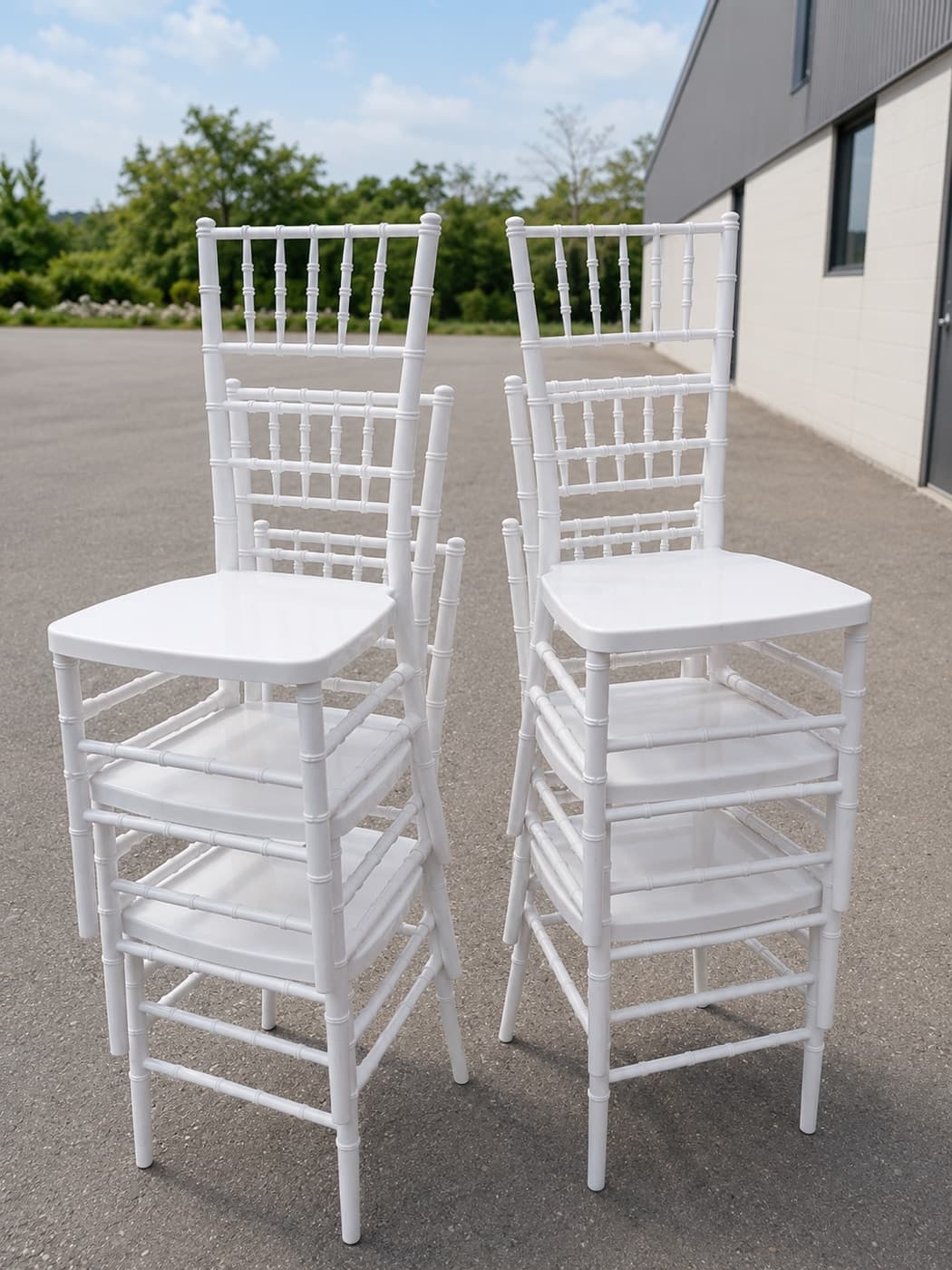 Matched white chiavari chairs, stacked outdoors